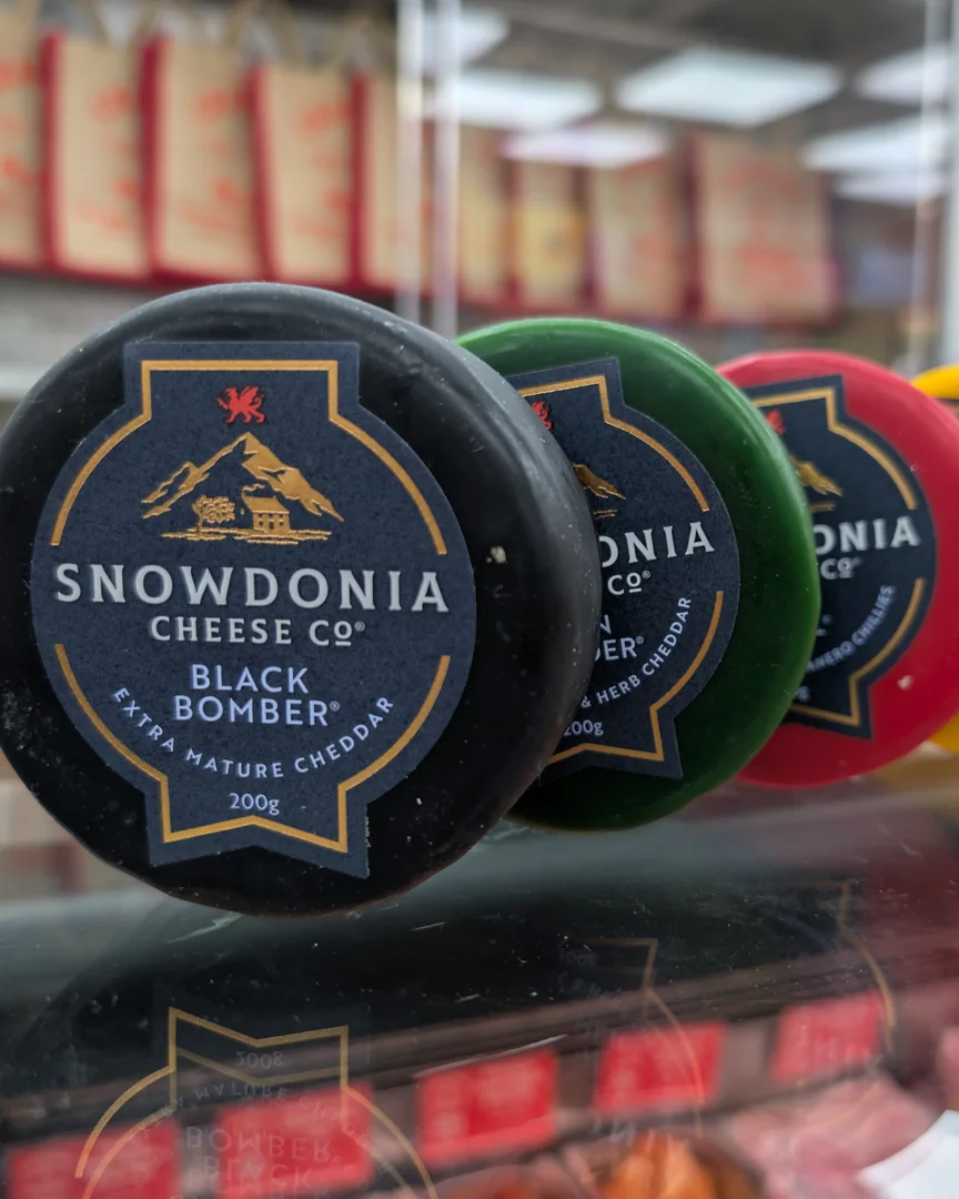A row of waxed Snowdonia Cheese Co truckles on the deli counter